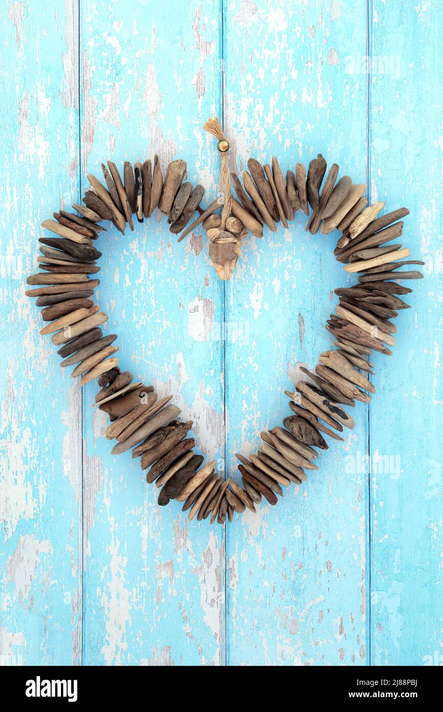 Sculpture de couronne en forme de coeur en bois de Driftwood sur bois bleu rustique. Littoral naturel et symbole romantique concept minimal. Flat lay, vue de dessus. Banque D'Images Sculpture de couronne en forme de coeur en bois de Driftwood sur bois bleu rustique. Littoral naturel et symbole romantique concept minimal. Flat lay, vue de dessus. Banque D'Images