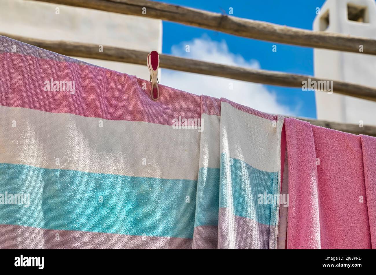 Serviettes de bain colorées accrochées à une corde à linge avec une épingle à linge. Mise au point sélective. Ciel nuageux et cheminée en arrière-plan. Banque D'Images