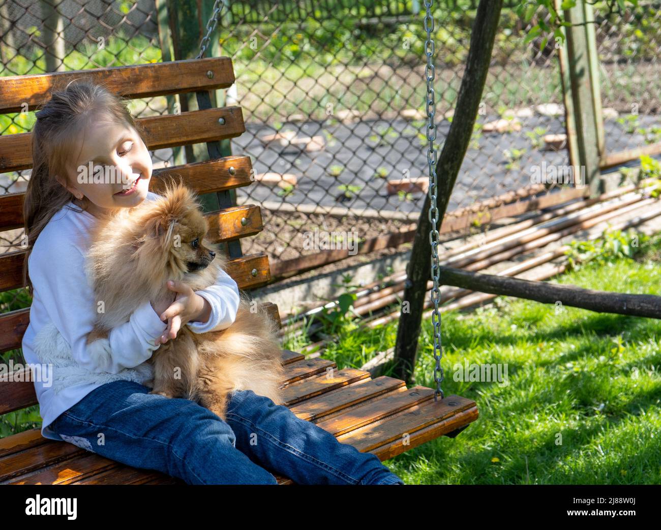 petite fille embrassant son chien tout en faisant une balançoire un jour de printemps Banque D'Images