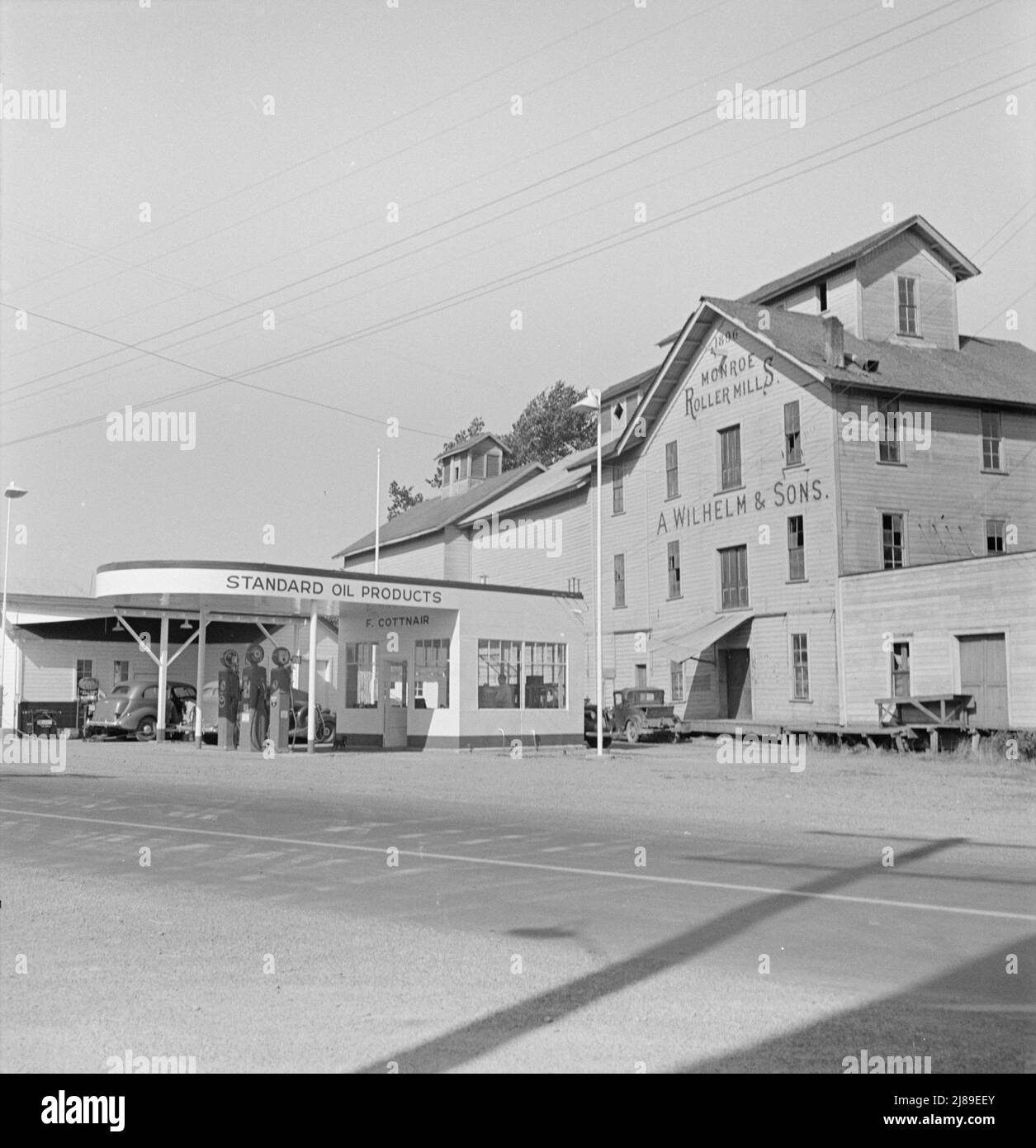 Oregon, Monroe, comté de Benton. L'usine de Wilhelm a fermé il y a dix ans et la station de service "était tout à fait un centre de commerce autour d'ici jusqu'à ce qu'ils aient de bonnes routes." [Station-service gérée par F. Cottnair, avec produits Standard Oil en vente; texte à l'avant de l'usine : « 1896 - Monroe Roller Mills - A. Wilhelm & amp; Sons »]. Banque D'Images