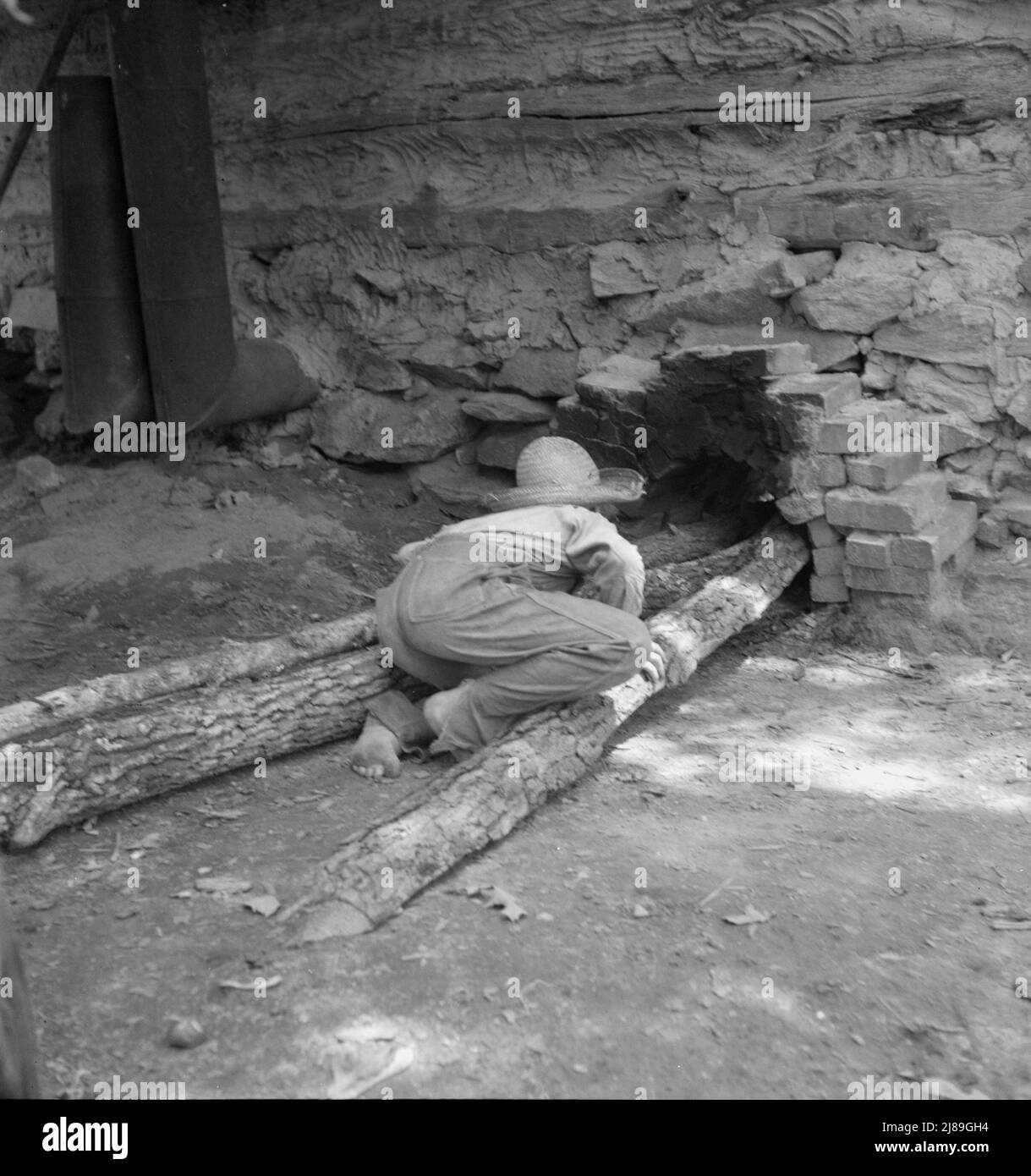 Fils de dix ans de tabac locataire tend le feu qui est de guérir le tabac dans la grange. Granville County, Caroline du Nord. Banque D'Images