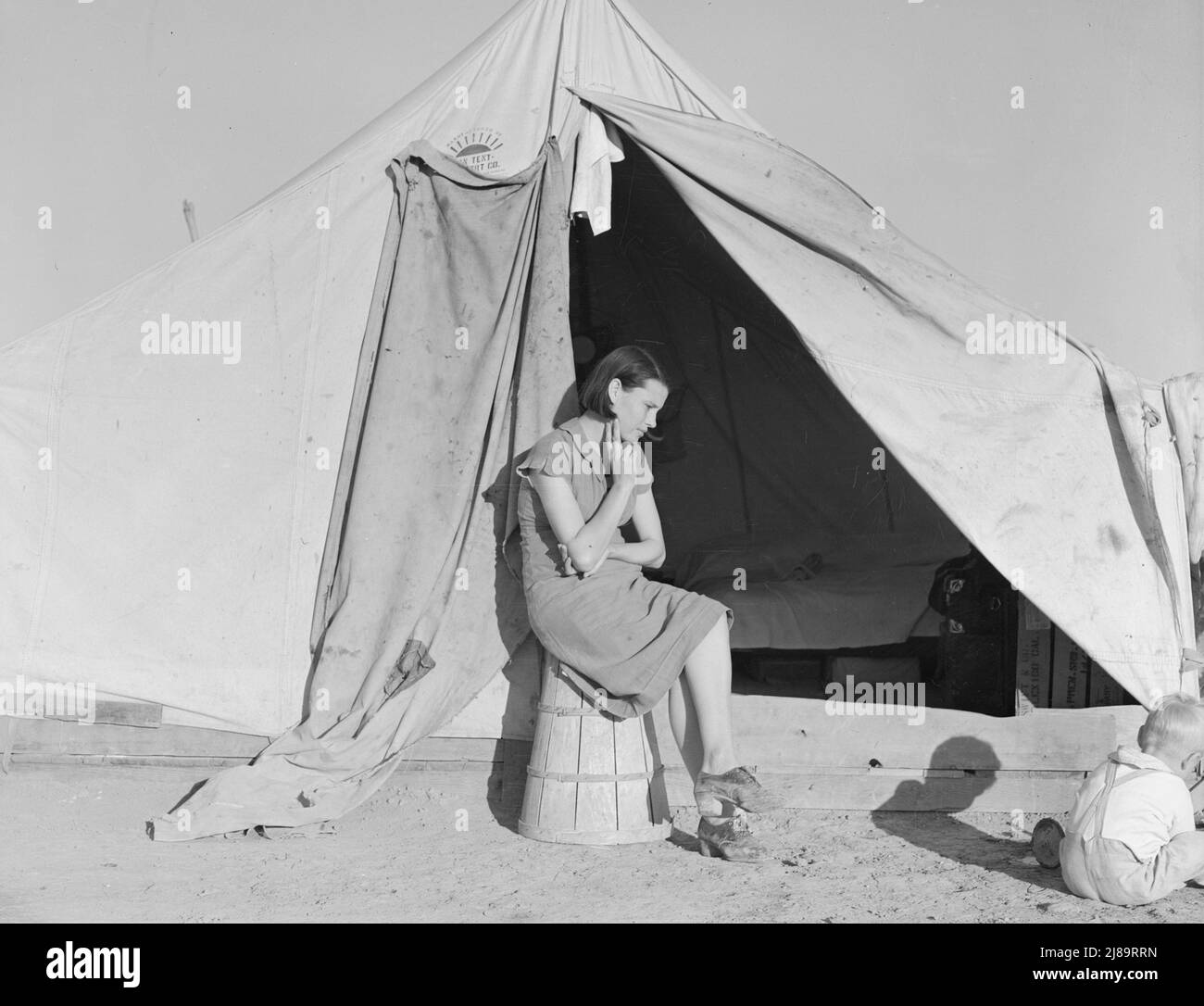 Jeune mère immigrée qui vit dans une des tentes. Californie. Camp d'urgence de la Farm Security Administration (FSA). Calipatria. [Notez que le panier de ramassage des pois retourné est utilisé comme siège]. Banque D'Images