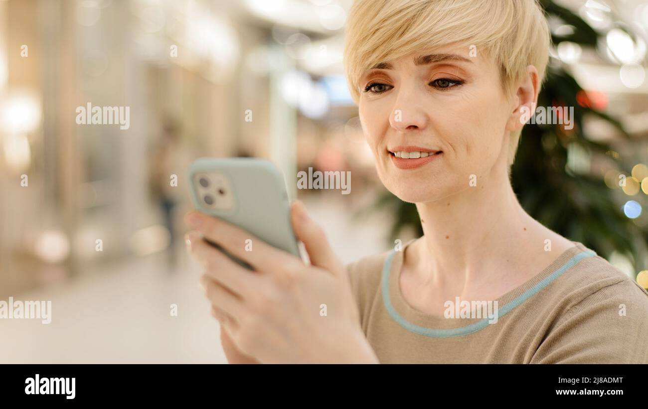 Portrait mature âge moyen femme caucasienne femme d'affaires avec téléphone mobile réservation en ligne commande de nourriture taxi acheter magasin en ligne en utilisant le chat Banque D'Images