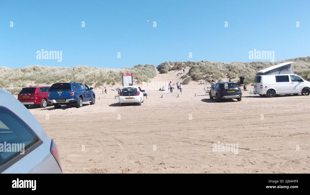 Voitures garées sur la plage avec des vacanciers profitant du soleil. Ciel bleu vif et espace de copie, Ainsdale, Royaume-Uni, Banque D'Images