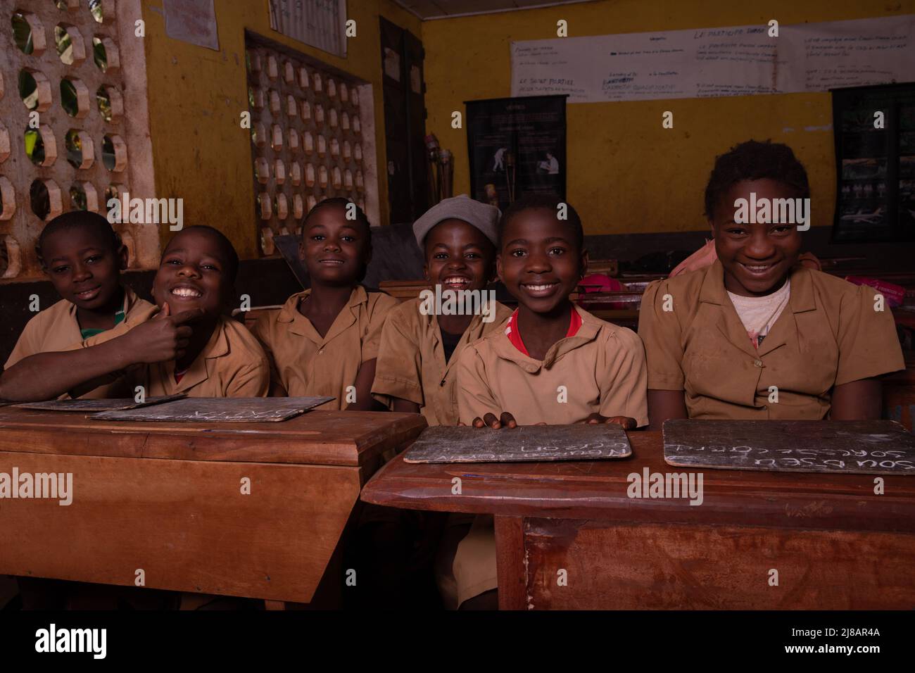 Groupe d'élèves assis aux bureaux de l'école avec leurs tableaux noirs heureux rire. Banque D'Images