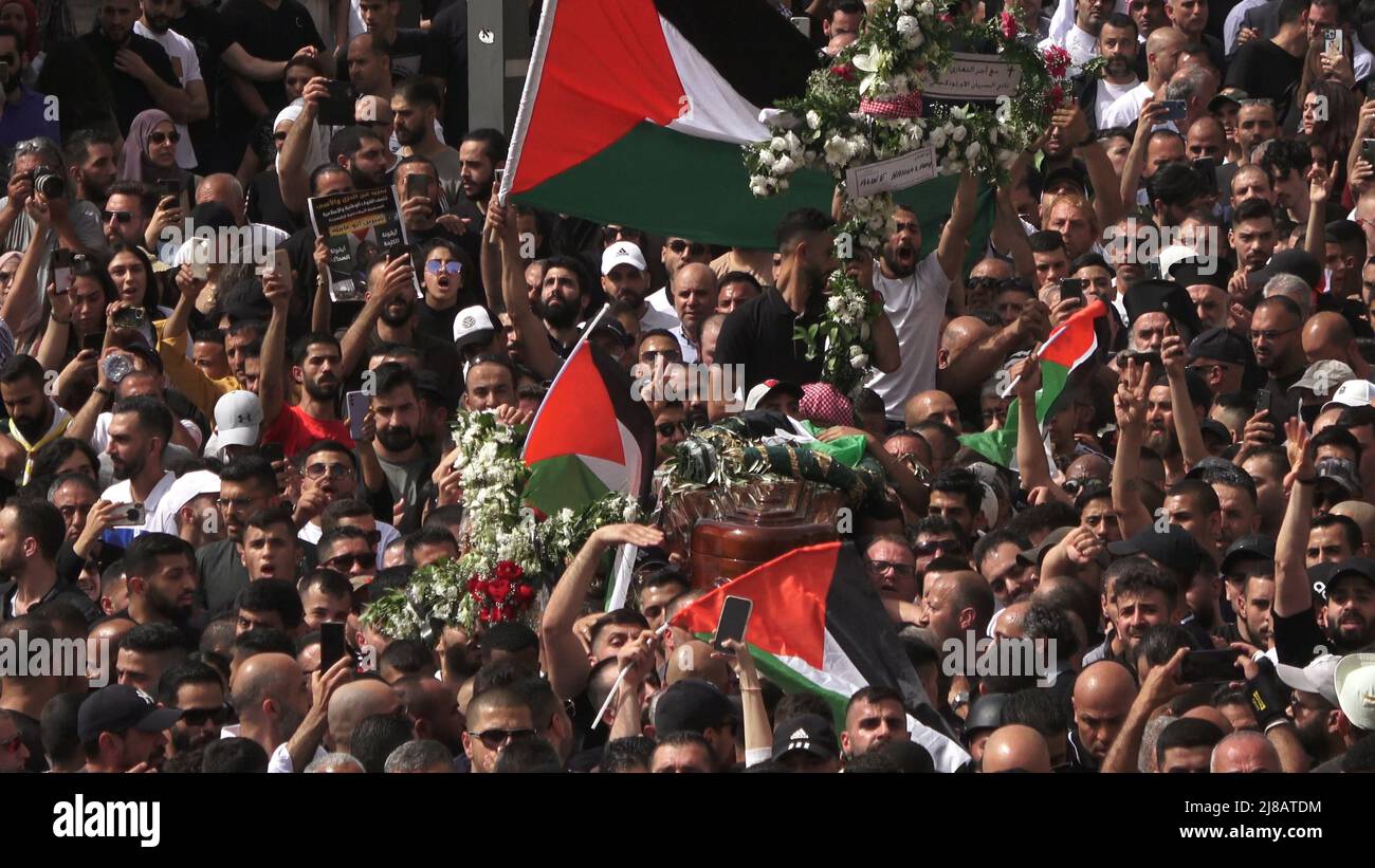 JÉRUSALEM, ISRAËL - 13 mai : les Palestiniens brandirent des drapeaux nationaux alors qu'ils portent le cercueil de Shireen Abu Aklel, journaliste assassine d'Al-Jazeera, pour inhumation dans un cimetière chrétien du mont Sion, sur 13 mai 2022, à Jérusalem, en Israël. La journaliste palestinienne américaine Shireen Abu Akleh a été tuée par balle alors qu'elle couvrait un raid militaire israélien dans la ville de Jénine, en Cisjordanie. Banque D'Images