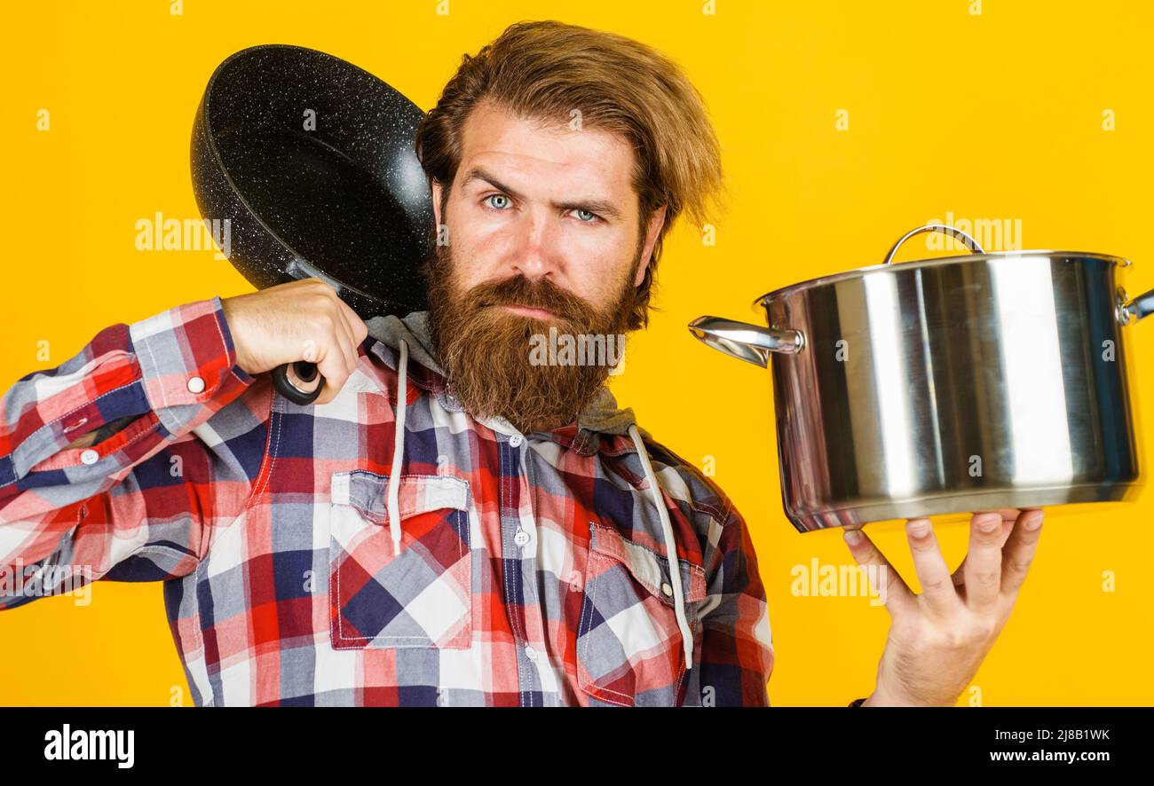Ustensiles de cuisine pour la préparation des aliments. Homme barbu avec frypan et pot. Poêle et casserole. Banque D'Images