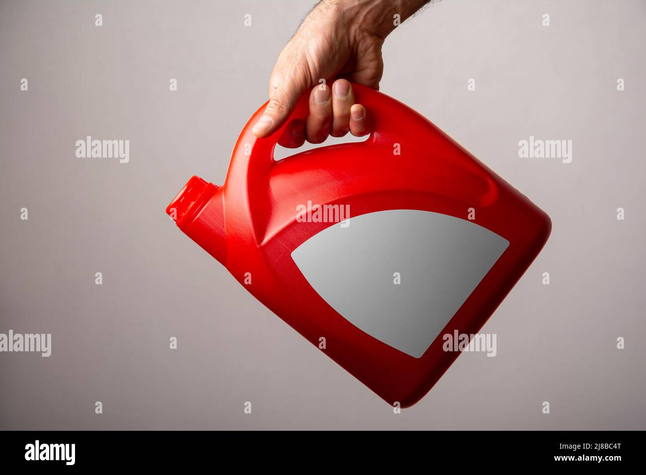 Un homme tenant une bouteille de détergent rouge de cuisine avec bouchon fermé, modèle de série maquette prêt pour votre conception. Chemin de sélection d'étiquette inclus. Banque D'Images