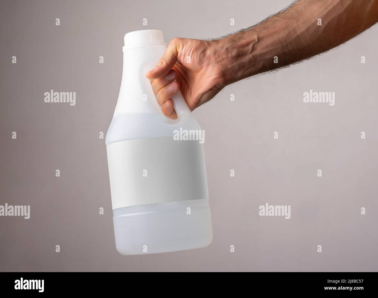 Une main d'homme tenant une bouteille de vinaigre avec étiquette vierge, modèle de série maquette prêt pour votre conception. Chemin de sélection d'étiquette inclus. Banque D'Images