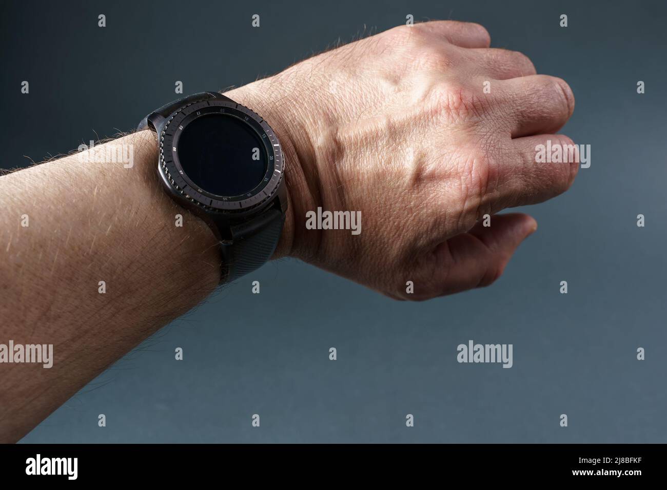 Montre intelligente avec écran noir sur la main d'un homme, gros plan sur fond gris. Banque D'Images