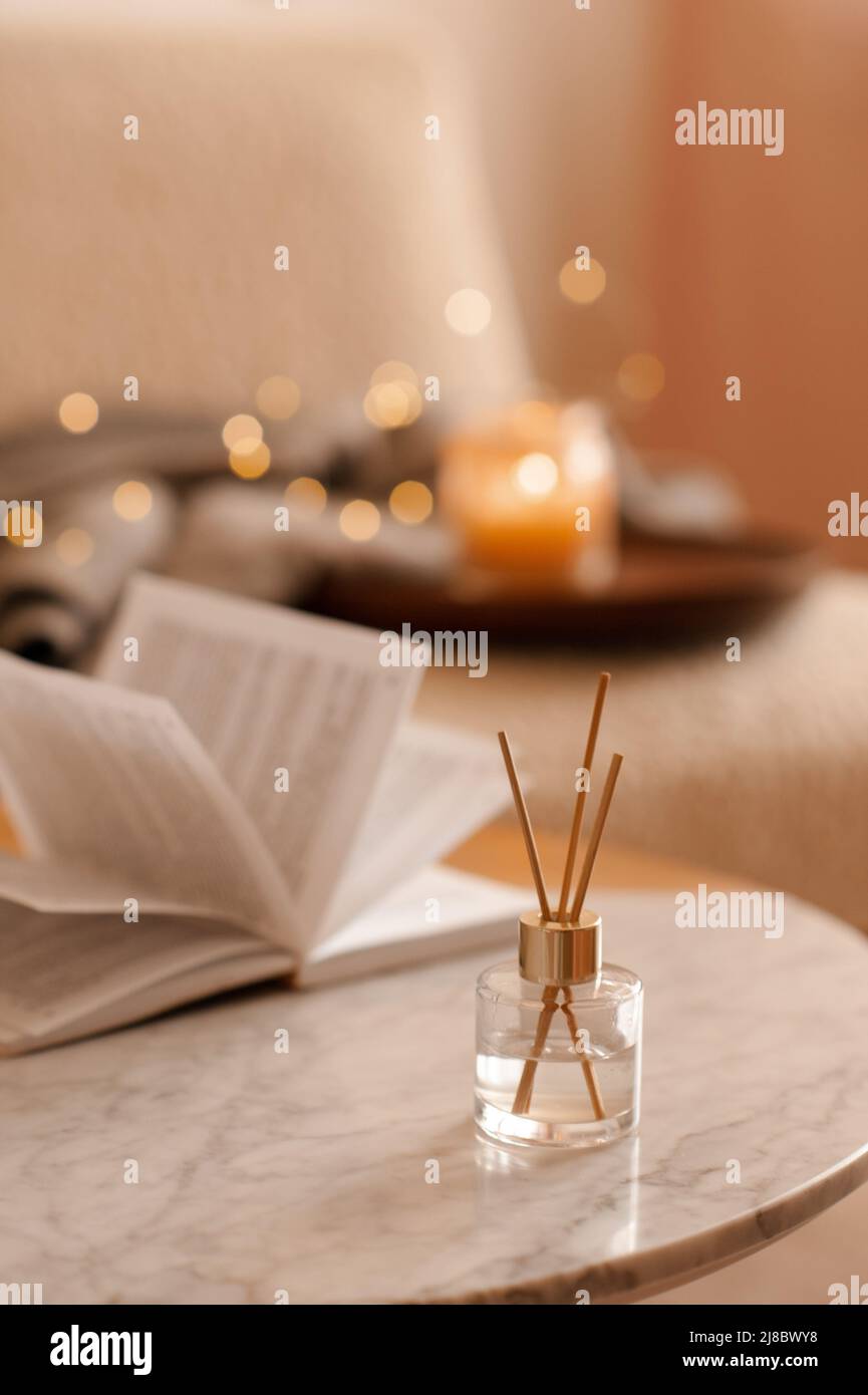 Parfum d'intérieur liquide dans diffuseur avec livre en papier ouvert sur  table basse dans la chambre à coucher à l'intérieur gros plan sur bougie  parfumée. Ambiance chaleureuse et relaxante. Aro Photo Stock -