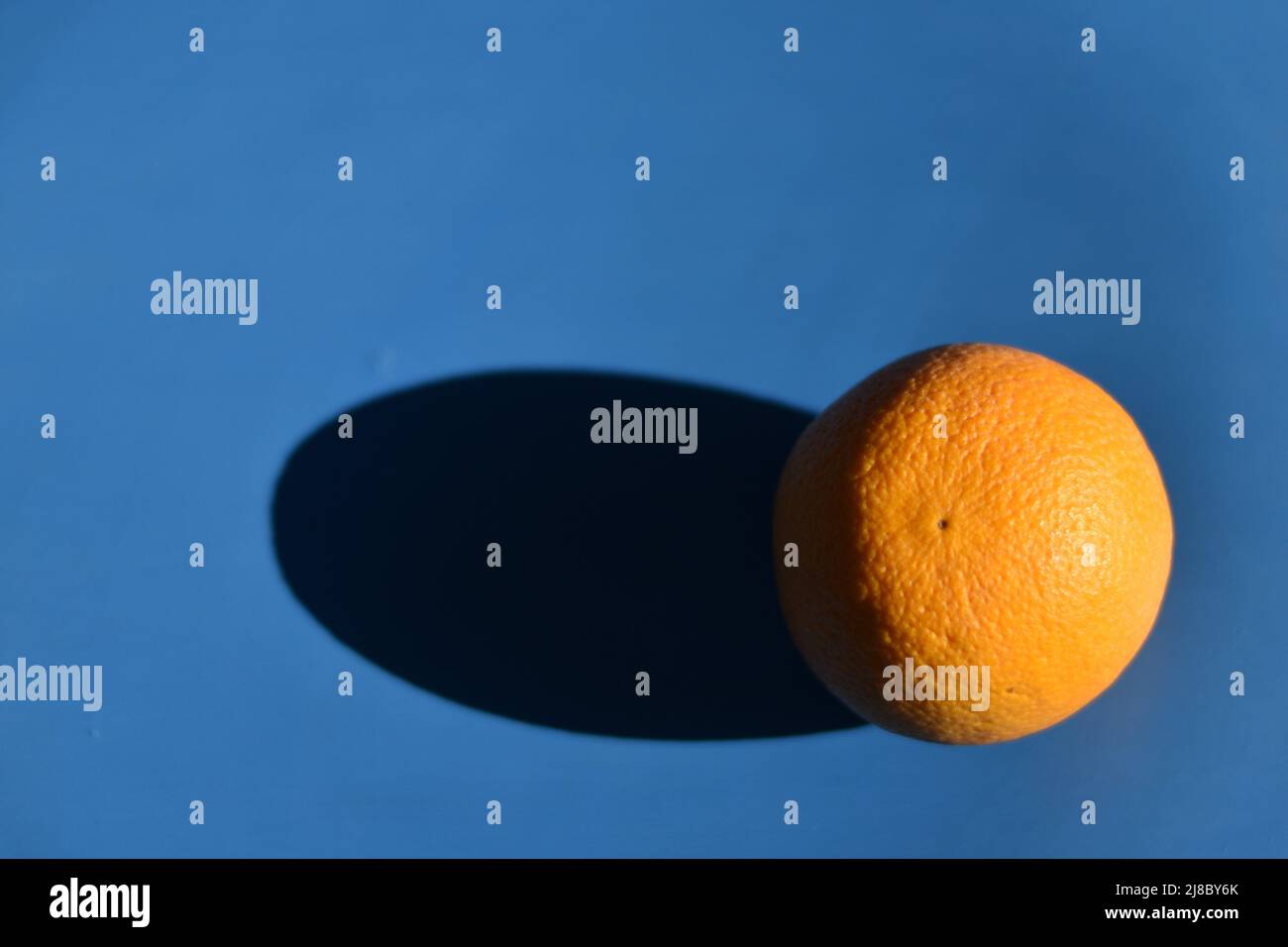 Orange mûr avec ombre sur fond bleu Banque D'Images