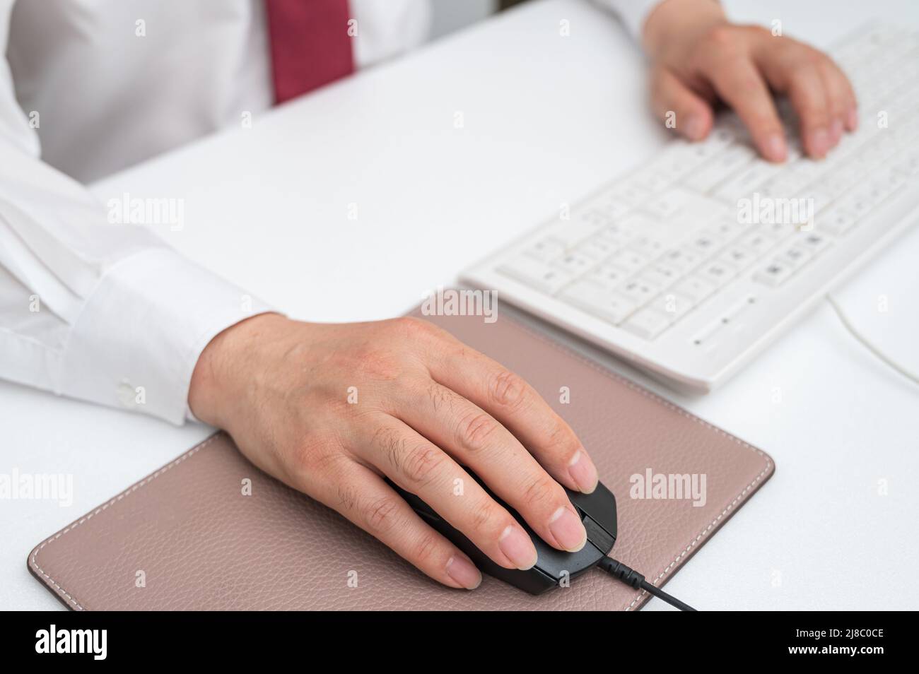 Main d'homme d'affaires tenant la souris d'ordinateur au bureau. Banque D'Images
