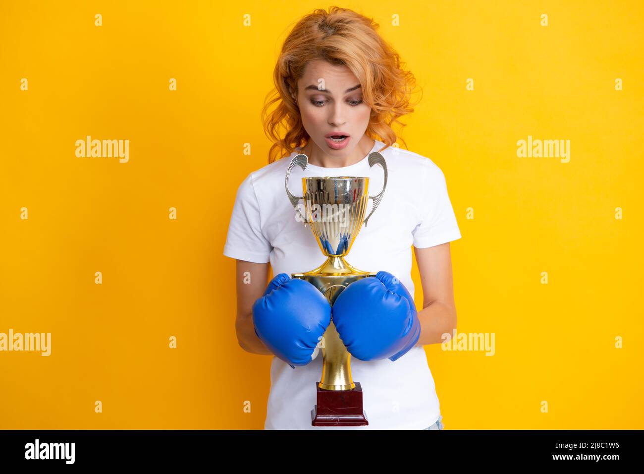 Portrait de drôle surpris femme gagnante dans des gants de boxe isolés sur  jaune. Une femme en gants de boxe tient la coupe gagnante du champion Photo  Stock - Alamy