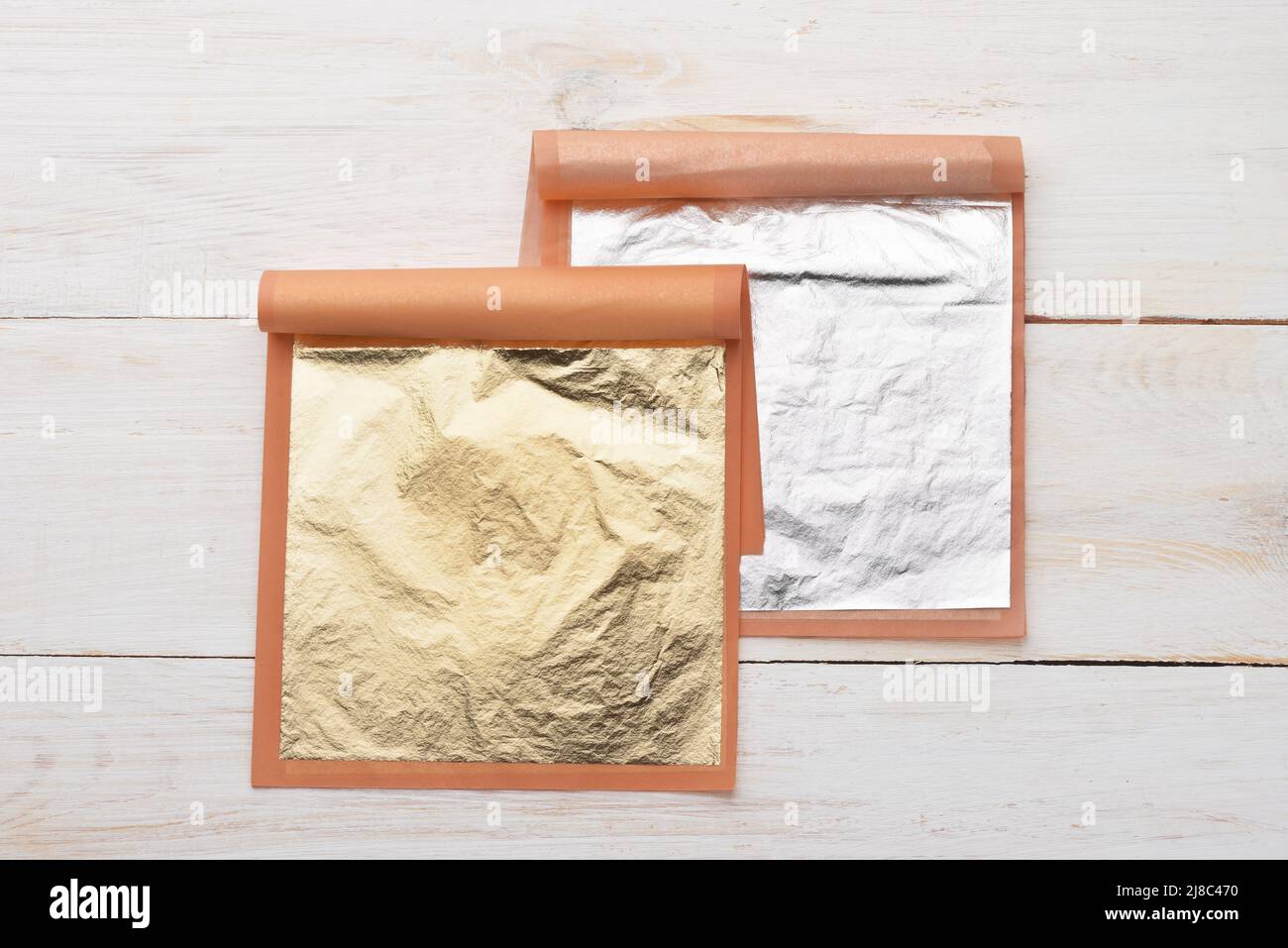 Vue de dessus de la nourriture naturelle comestible feuilles d'or et d'argent sur fond de bois blanc Banque D'Images