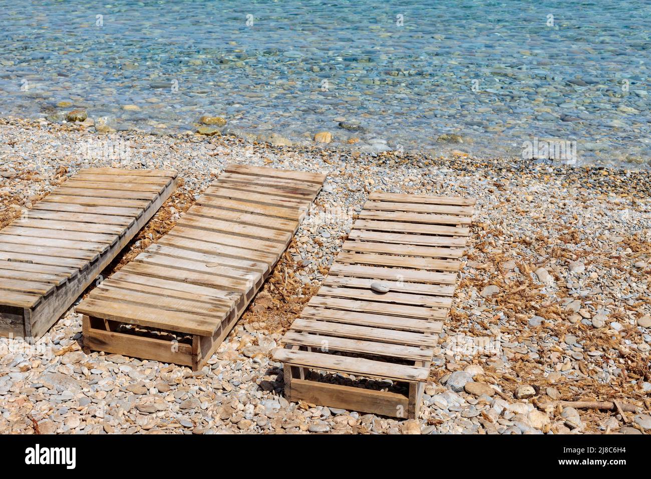 Deux chaises longues en bois sur une plage de galets. Chaises longues sur la mer par une journée ensoleillée. Concept vacances d'été avec chaises longues Banque D'Images