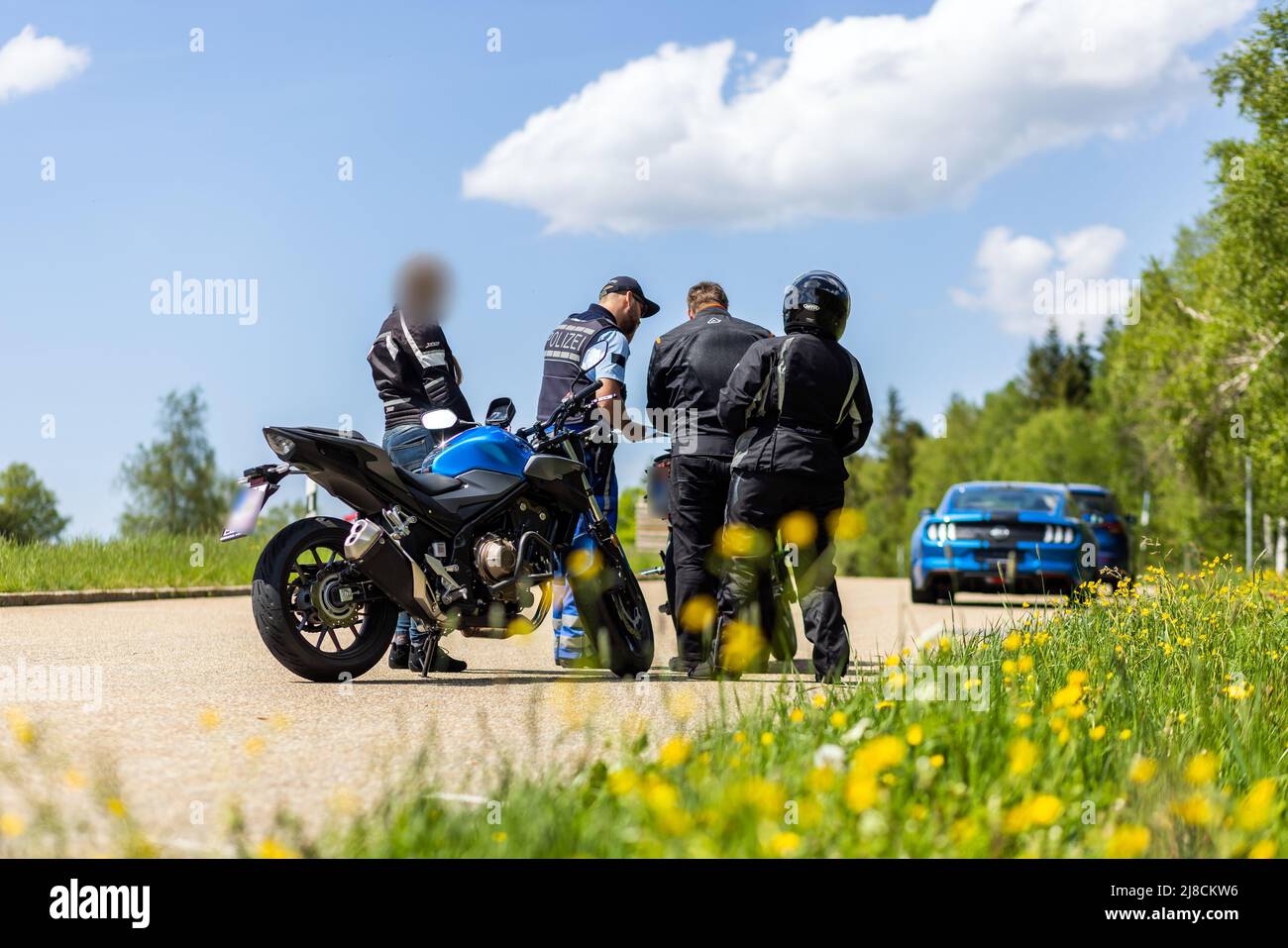 15 mai 2022, Bade-Wurtemberg, Pforzheim: Un policier se tient à côté de trois motocyclistes pendant un contrôle. Le siège de la police de Pforzheim effectue aujourd'hui un contrôle à grande échelle de la moto sur le B500 dans le district de Freudenstadt. Photo: Philipp von Ditfurth/dpa Banque D'Images
