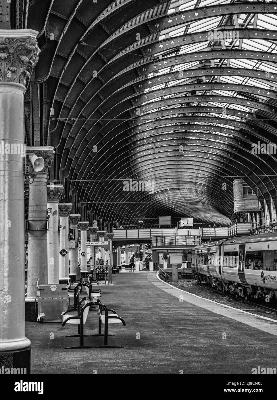 Une plate-forme de gare avec un train d'un côté et une ligne de colonnes de l'autre. Une passerelle se trouve à distance. Banque D'Images