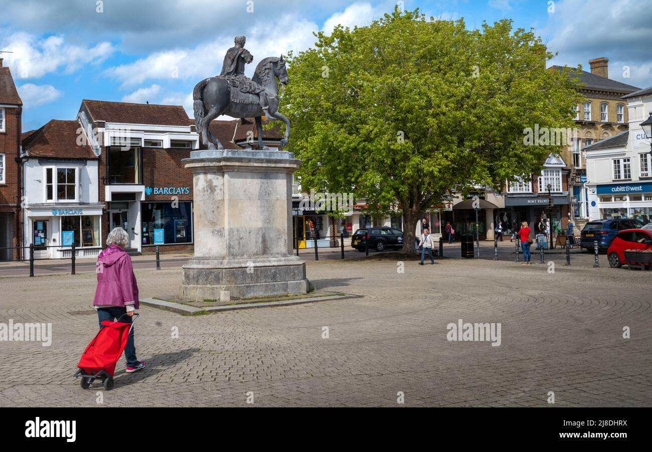 Une femme avec un chariot à provisions passe devant la statue du roi William III sur un cheval sur la place de la ville de Petersfield dans le Hampshire, en Angleterre Banque D'Images
