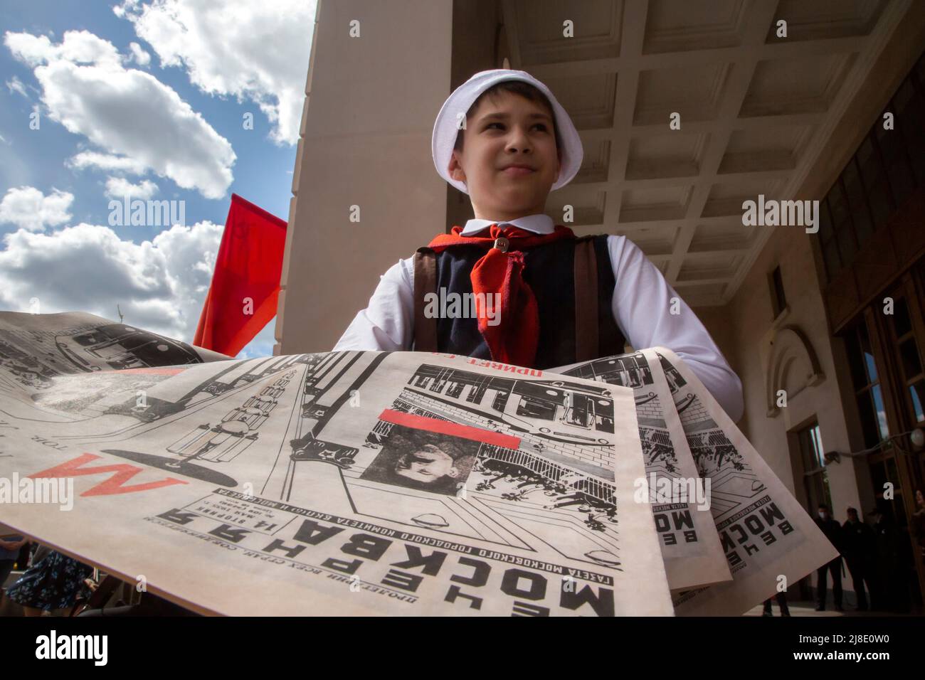 Moscou, Russie. 15th mai 2022. Un garçon habillé comme un pionnier du 1930 distribue les journaux Vechernaya Moskva 14 mai 1935 numéro avec des informations sur l'ouverture du métro à Moscou. La station Park Kultury ré-enactes, dans une rue avant une entrée à la station, la cérémonie de 1935 pour lancer la première ligne de l'histoire afin de célébrer l'anniversaire 87th du métro de Moscou, Russie Banque D'Images
