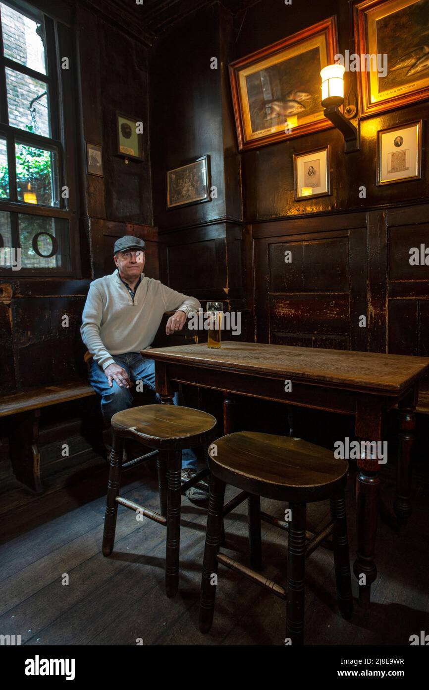 Un homme boit de la bière dans un pub traditionnel, le Ye Olde Cheshire Cheese The City of London, Royaume-Uni Banque D'Images