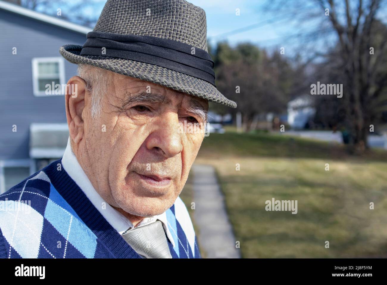 homme caucasien adulte âgé avec gilet décoratif en forme de losange bleu et cravate et chemise sur une rue de banlieue Banque D'Images