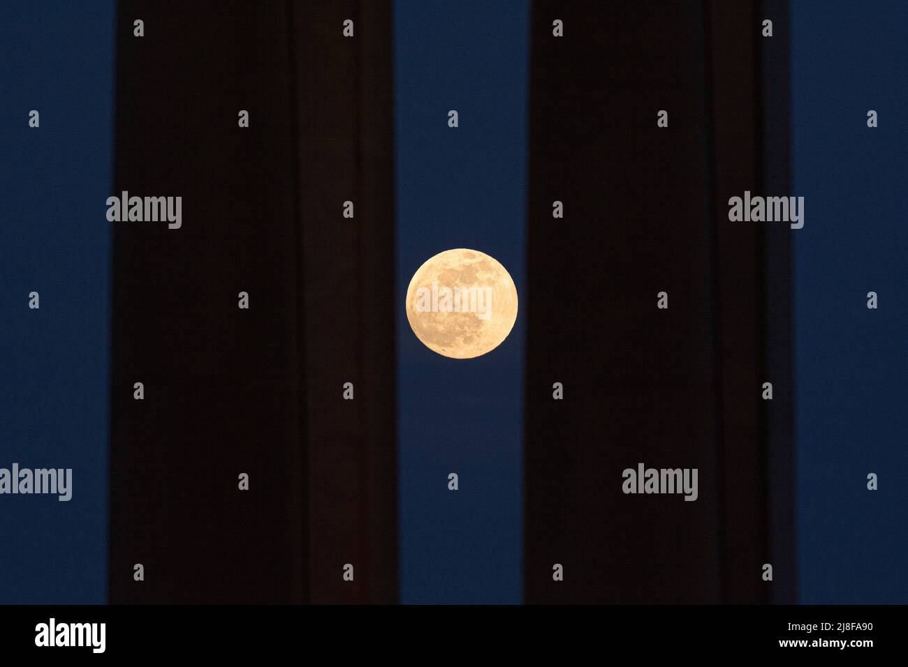 Malaga, Espagne. 15th mai 2022. La pleine lune, connue sous le nom de « lune rouge de sang », s'élève derrière deux colonnes avant une éclipse lunaire totale. Dans la nuit du 16 mai, une éclipse lunaire totale apparaîtra dans le ciel nocturne et sera visible en Europe. Au cours de l'éclipse lunaire totale, la lumière de la lune reflète une lumière rouge et orange. Crédit : SOPA Images Limited/Alamy Live News Banque D'Images