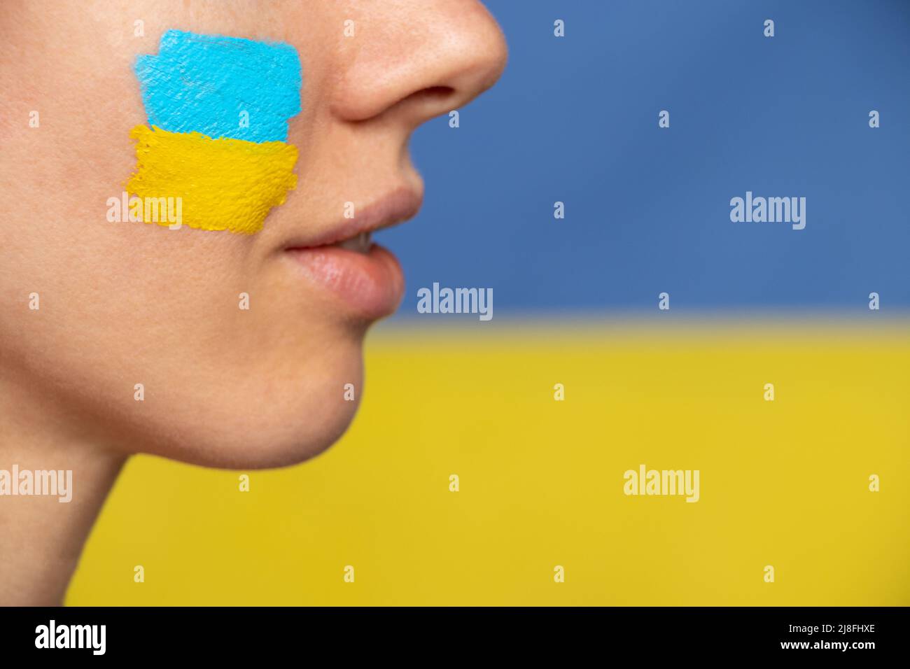 Le visage d'une fille avec le drapeau national de l'Ukraine jaune-bleu sur son visage, patriote, la paix en Ukraine, la loi martiale Banque D'Images