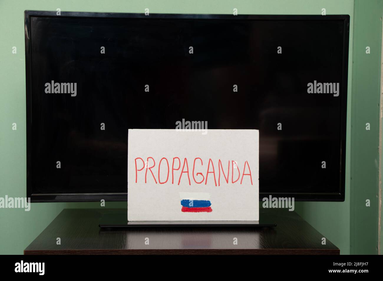Le mot propagande et le drapeau de la Russie est écrit sur une plaque qui est accroché à la télévision, propagande russe être prudent, arrêter la guerre en Ukraine Banque D'Images