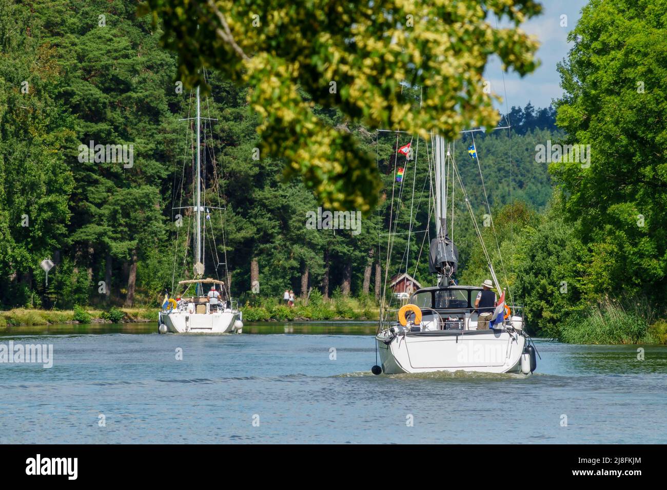 Voiliers dans un canal luxuriant en été Banque D'Images