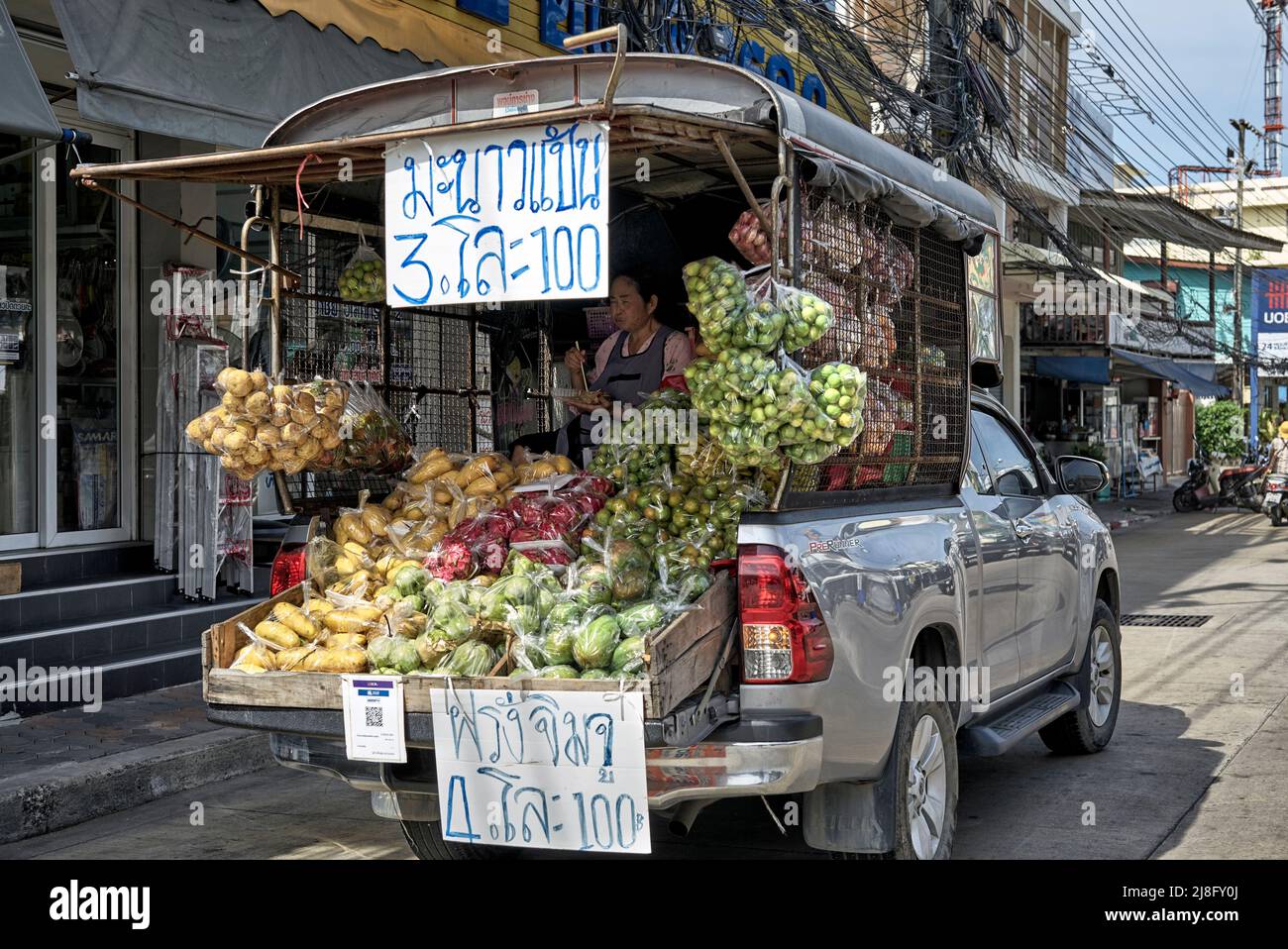 Véhicule alimentaire mobile. Fruits et légumes vendus à l'arrière d'un pick-up avec une femme âgée en présence. Thaïlande Asie du Sud-est Banque D'Images
