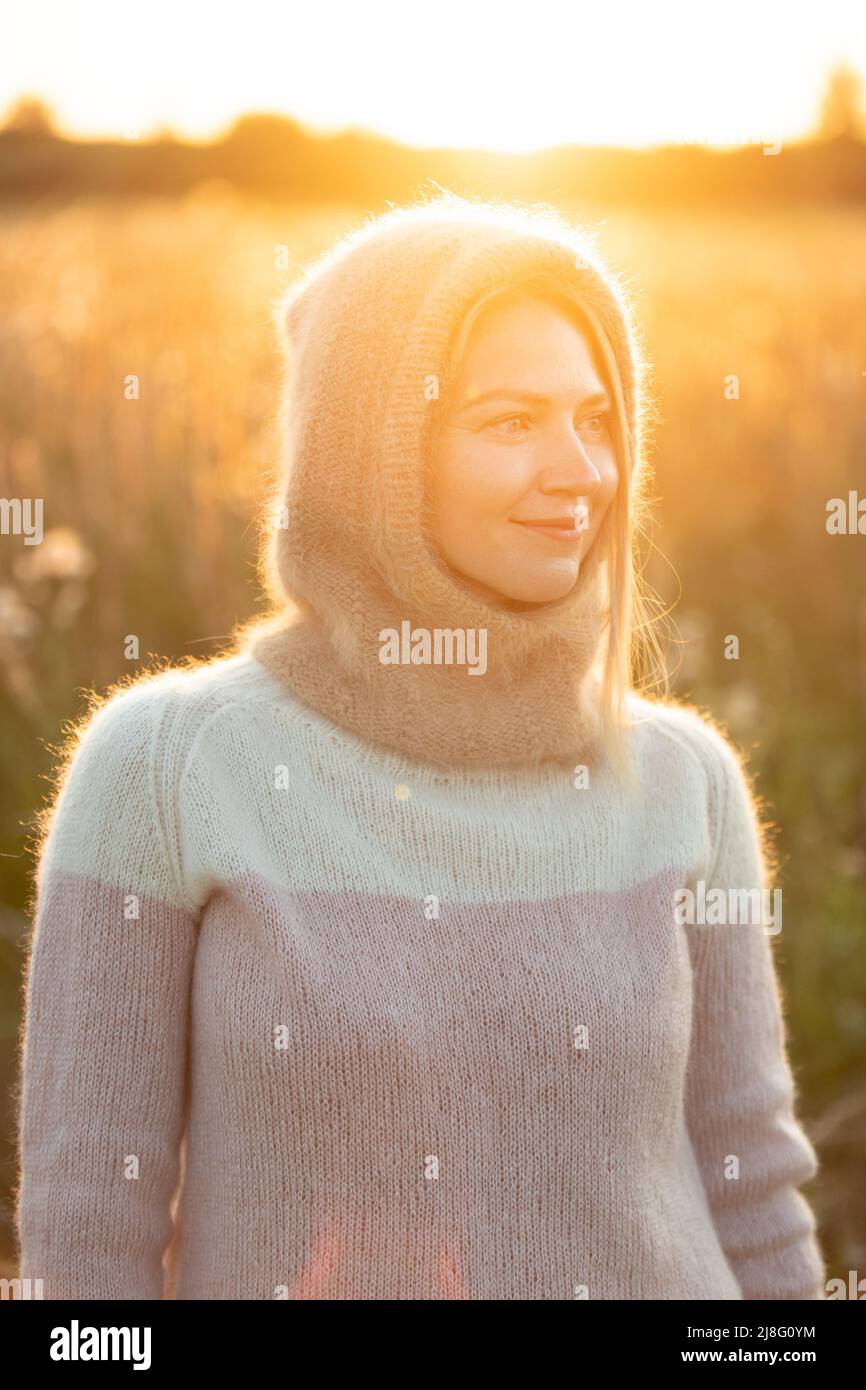 Portrait d'une jeune fille heureuse de race blanche en blouse de laine et bonnet tricoté marron posant dans la forêt du début du printemps en Sunny Day. Profitez-en Banque D'Images