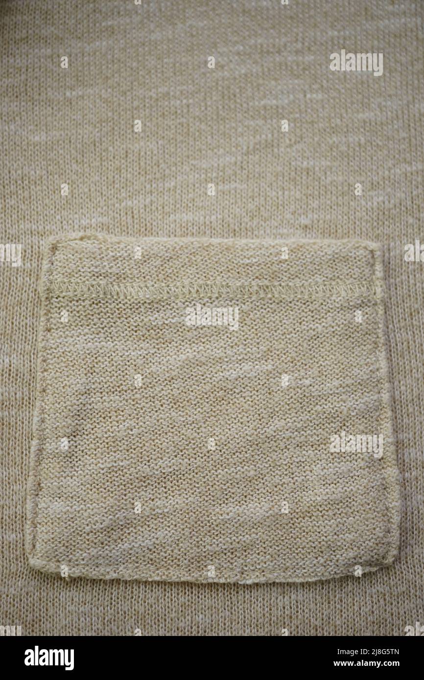 Pull beige avec poche, fond crème tricoté Banque D'Images