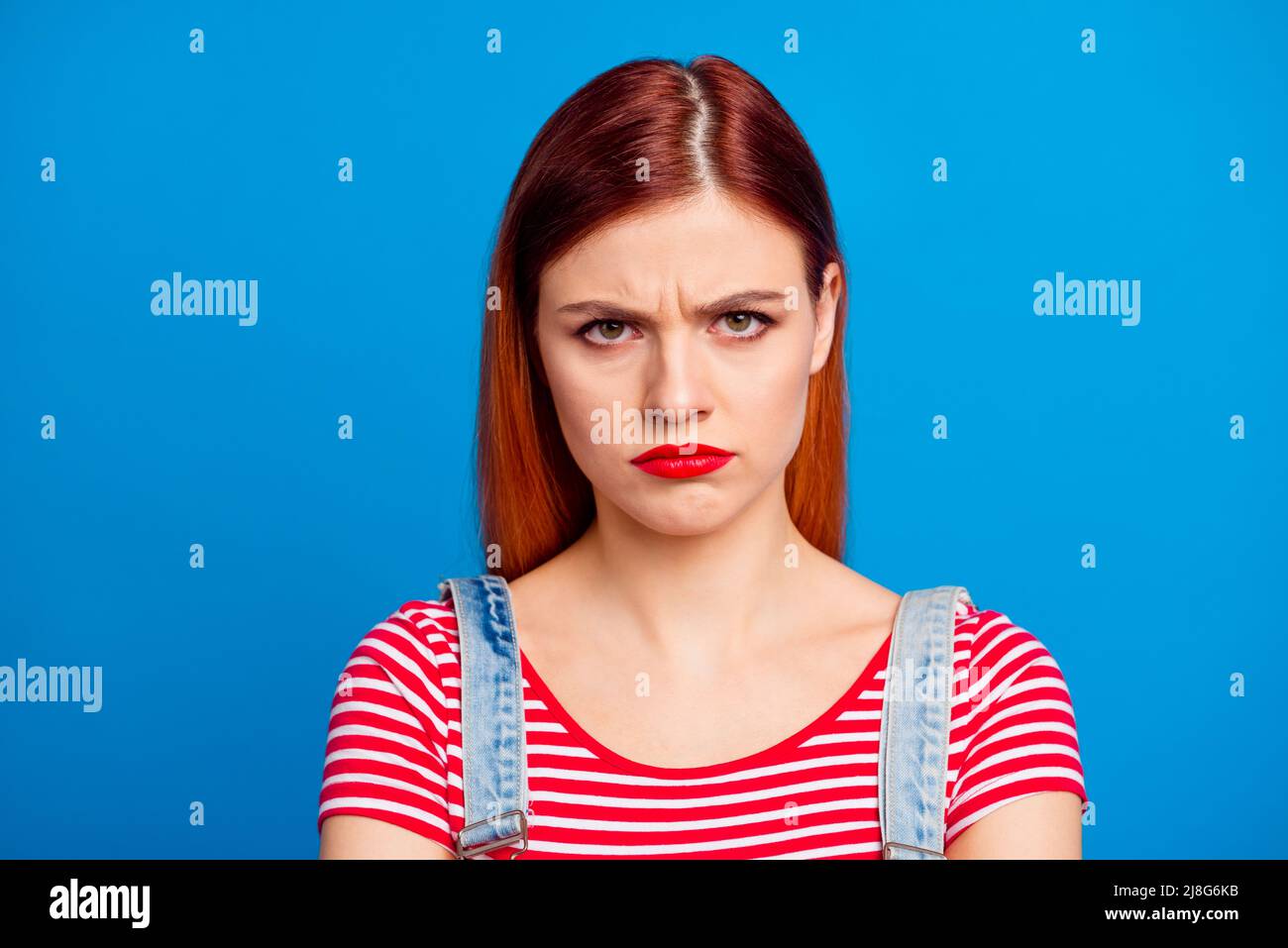 Portrait de jeune fille imsatisfaite visage sullen regarder caméra isolée sur fond bleu de couleur Banque D'Images