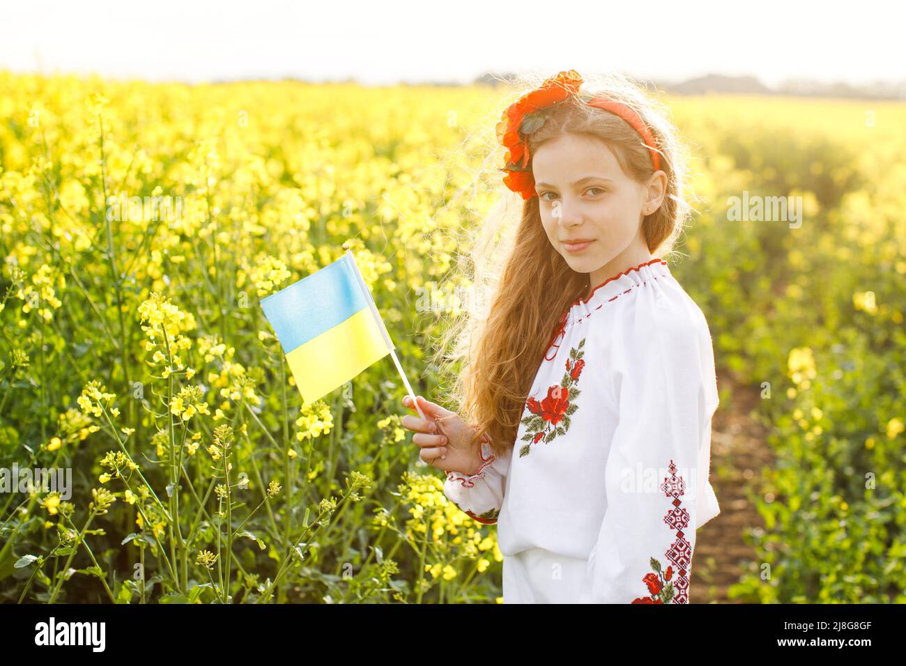 Priez pour l'Ukraine. Enfant avec drapeau ukrainien dans champ de colza. Petite fille tenant le drapeau national dans sa main. Banque D'Images