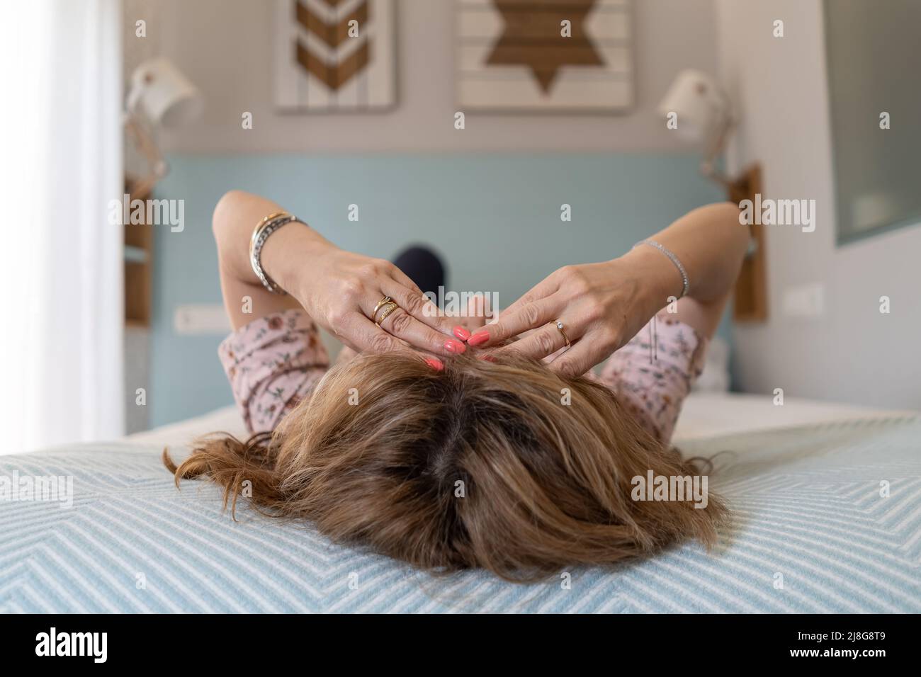 Femme couchée sur le lit avec un mal de tête sévère et les mains sur son front. Banque D'Images