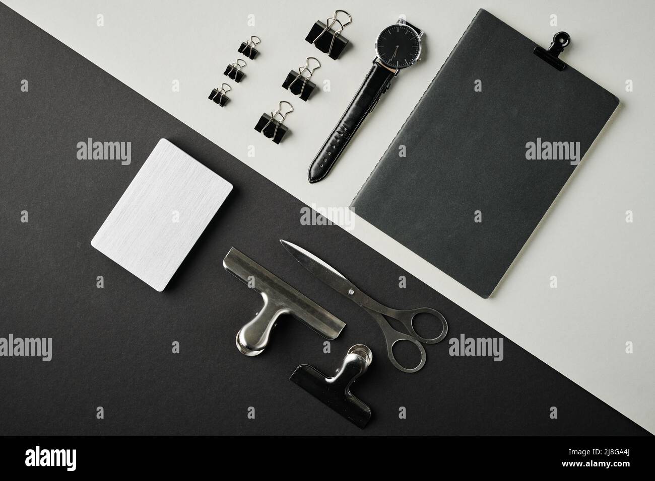 Présentation du bloc-notes noir, de la montre-bracelet, de l'ensemble de clips, des ciseaux et du bloc-notes blanc sur un fond contrasté ou sur le lieu de travail d'un professionnel Banque D'Images