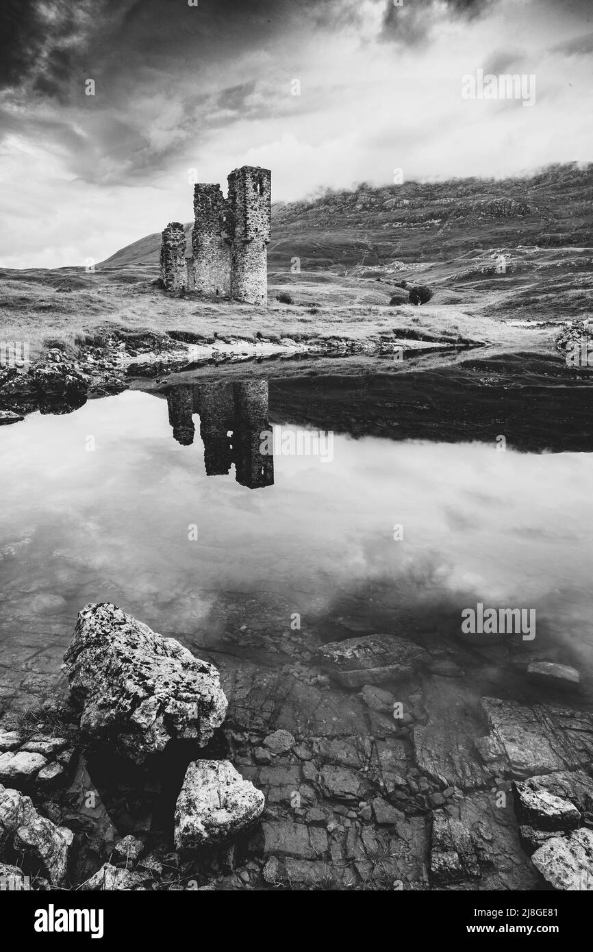 Une photo en noir et blanc d'un vieux château d'Écosse avec une réflexion dans l'eau. Banque D'Images