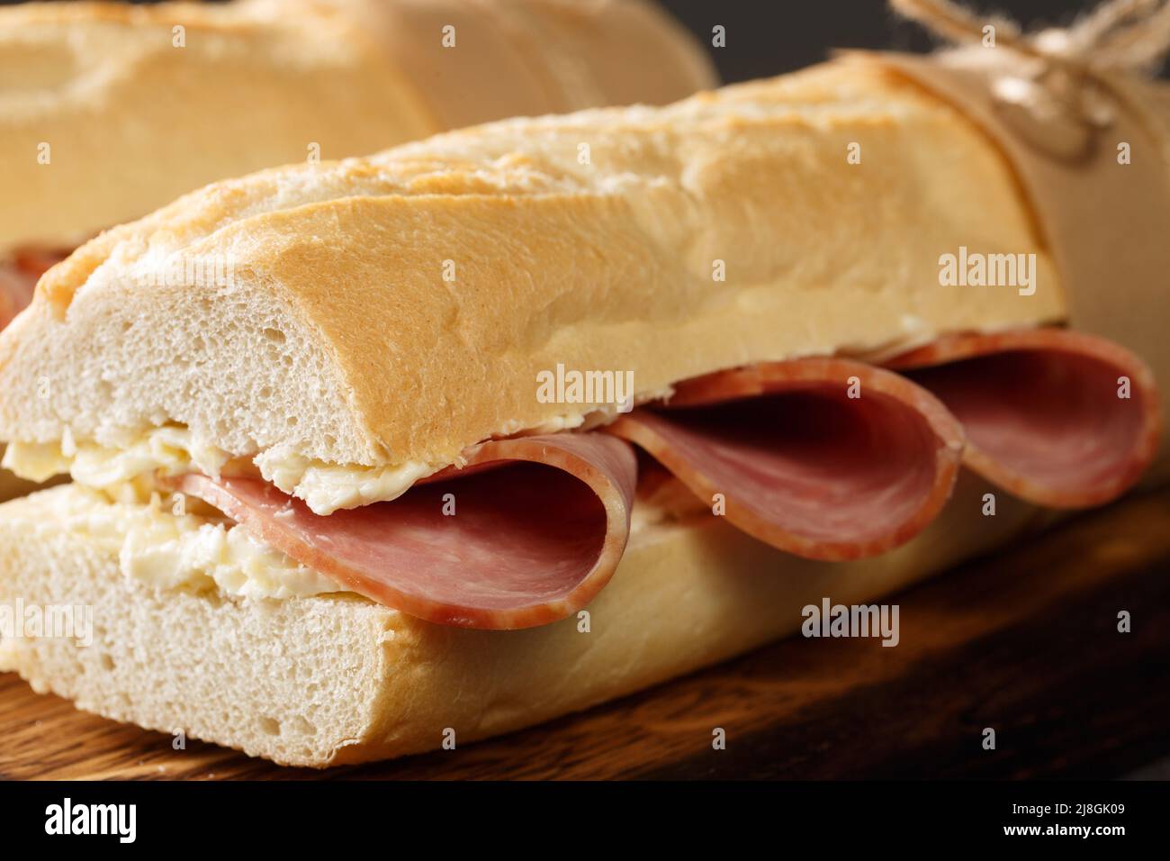 Sandwich français baguette croustillante, beurre légèrement salé et jambon finement tranché, idéalement Jambon de Paris à proximité sur le panneau en bois. Horizontale Banque D'Images