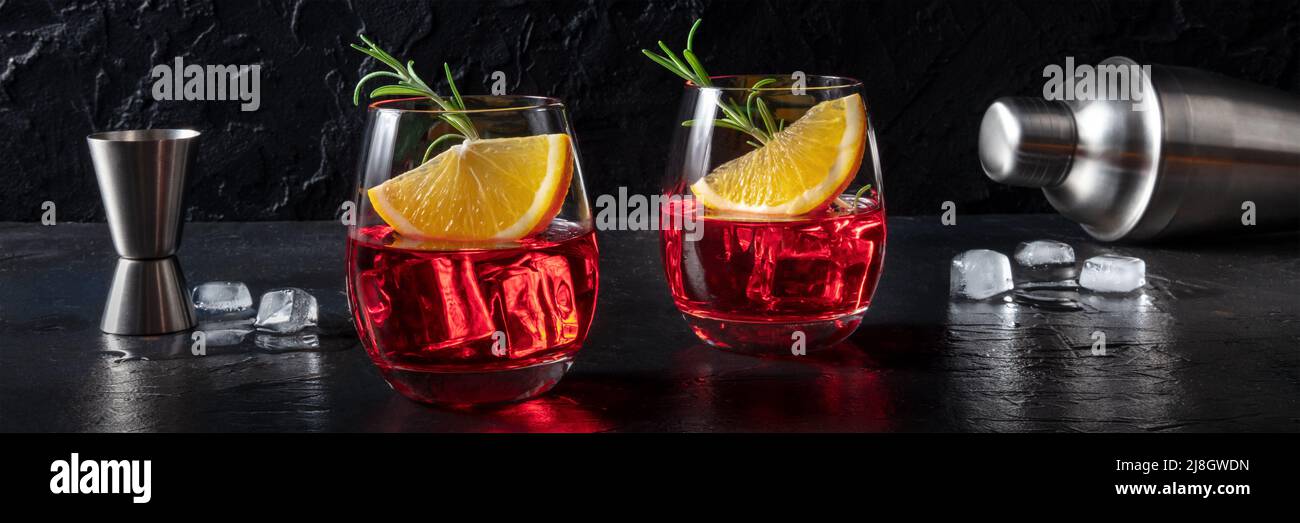 Cocktails Campari avec des oranges fraîches, du romarin, un jigger et un shaker, un panorama sur un fond d'ardoise noire Banque D'Images