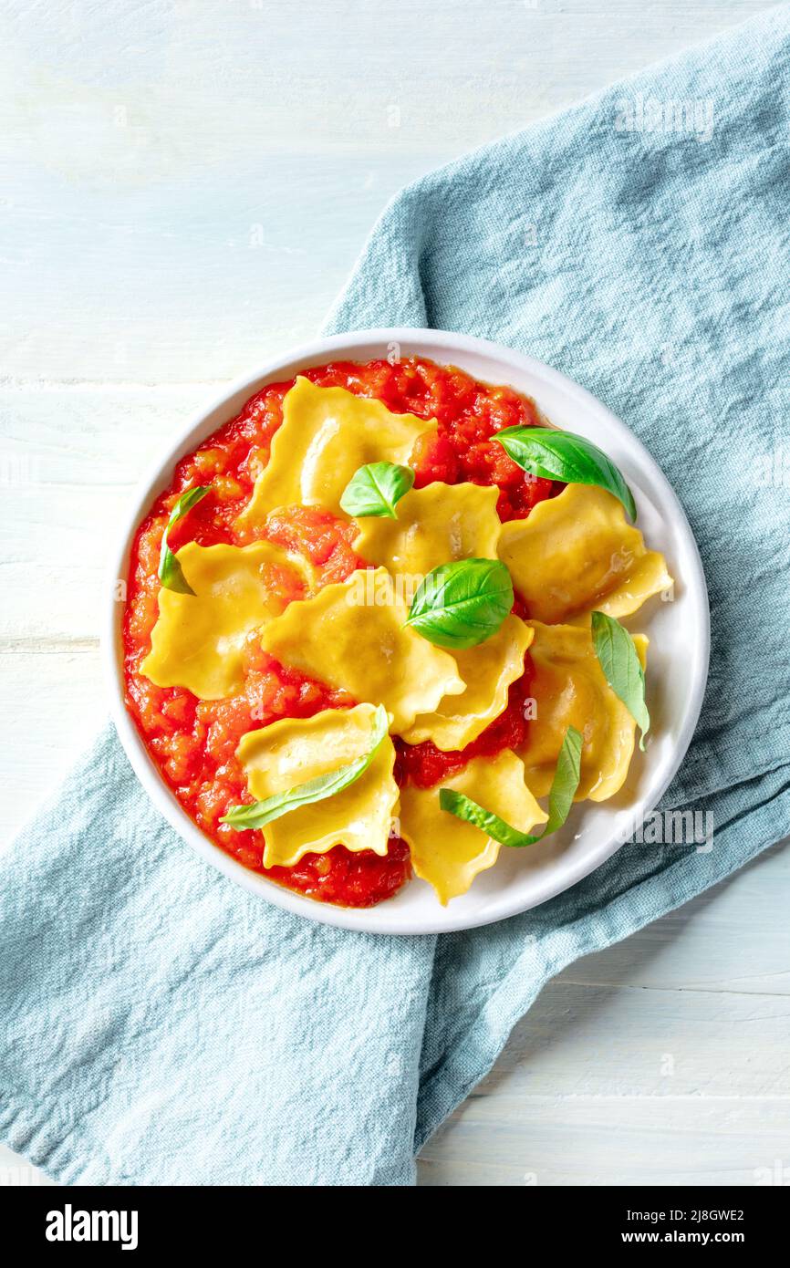 Raviolis à la sauce tomate et feuilles de basilic frais sur une assiette, au-dessus de la tête plat déposer le grenaille sur un fond de bois rustique Banque D'Images