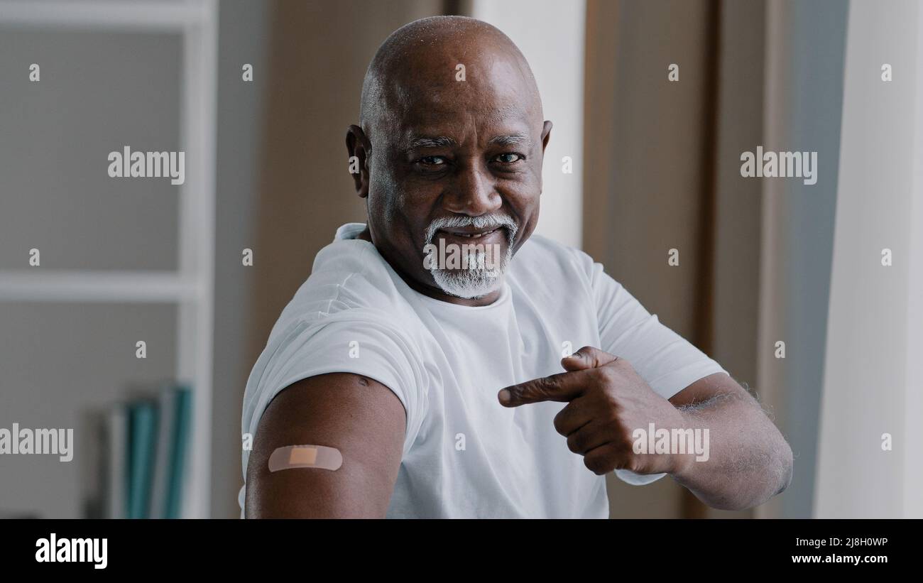 Portrait afro-américain ancien homme mature senior patient montre le plâtre médical sur l'épaule démontre la marque d'injection client mâle satisfait après Banque D'Images