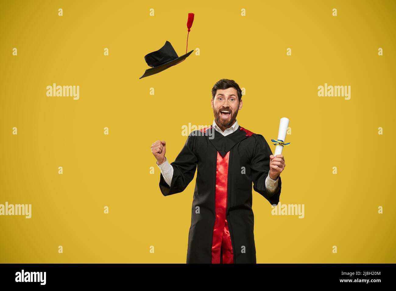 Vue de face de l'étudiant avec la barbe finissant, le diplôme de lancer. Homme avec baccalauréat, master diplôme heureux, souriant, montrant hurray. Concept de goélette haute Banque D'Images Vue de face de l'étudiant avec la barbe finissant, le diplôme de lancer. Homme avec baccalauréat, master diplôme heureux, souriant, montrant hurray. Concept de goélette haute Banque D'Images