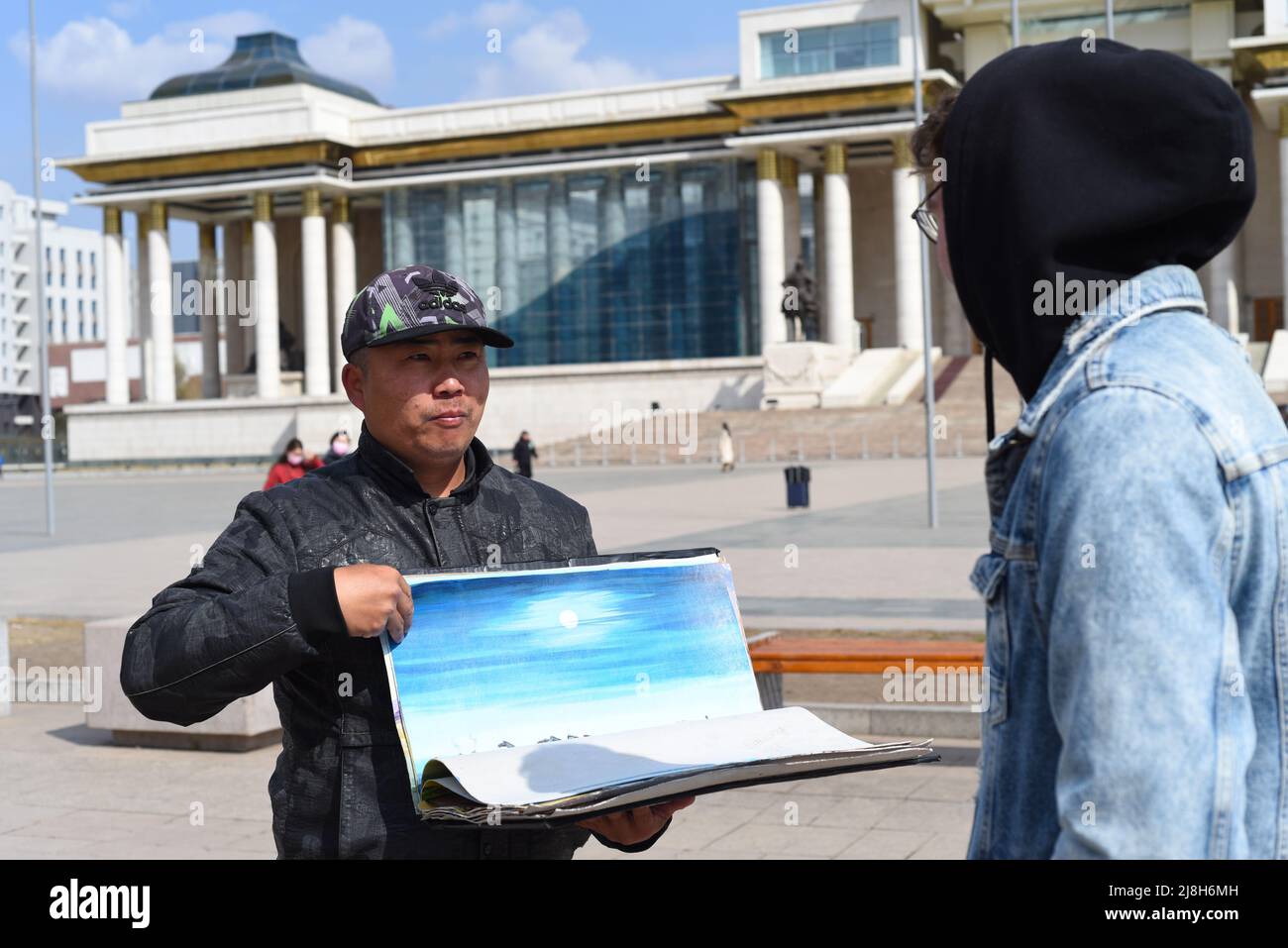 Oulan Baatar, Mongolie - 05.11.2022: L'homme mongol montre des souvenirs à un touriste à vendre Banque D'Images