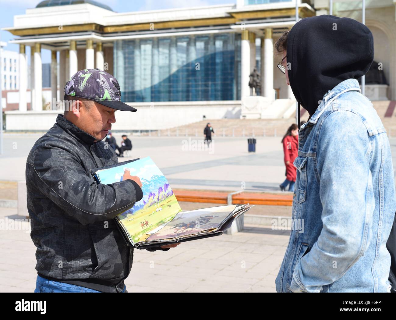 Oulan Baatar, Mongolie - 05.11.2022: L'homme mongol montre des souvenirs à un touriste à vendre Banque D'Images
