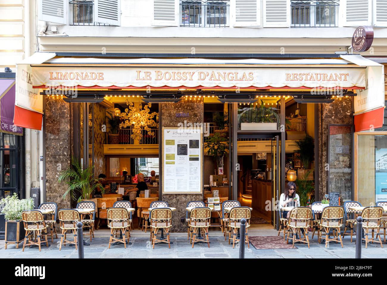 Femme avec téléphone portable assise au Boissy d'Anglas dans le 8th arrondissement, Paris, Ile-de-France, France Banque D'Images