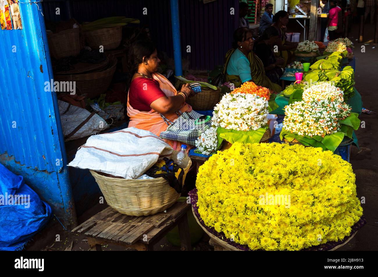 Mysore, Karnataka, Inde : Une femme s'assoit dans un stand de fleurs au marché de Devaraja. Banque D'Images