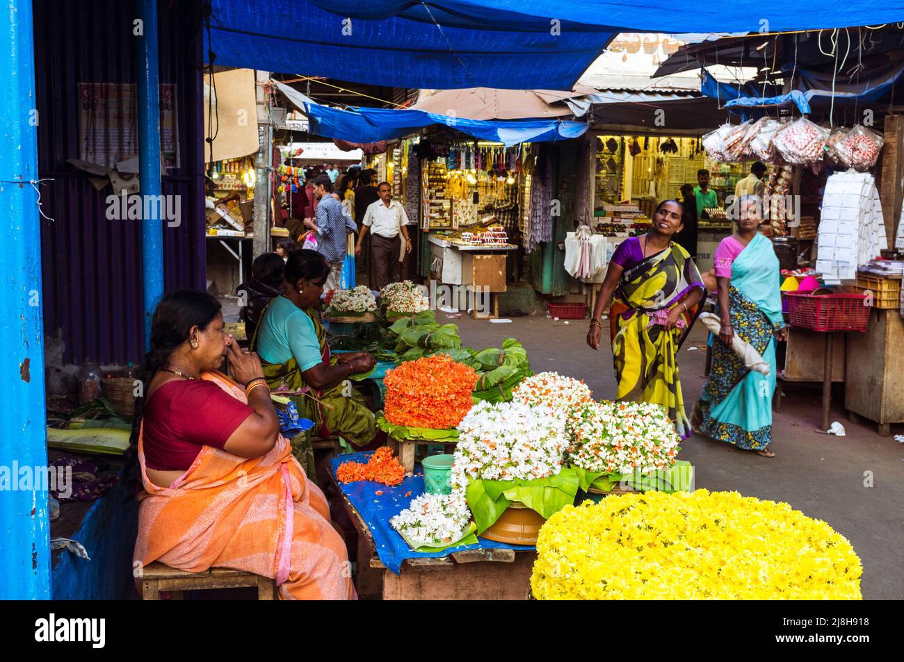Mysore, Karnataka, Inde : les femmes marchent devant les étals de fleurs au marché de Devaraja. Banque D'Images