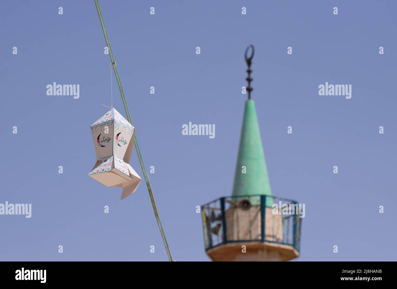Lanterne de Ramadan suspendue décorations de rue avec le minaret d'une mosquée en arrière-plan contre un ciel bleu en Jordanie au Moyen-Orient Banque D'Images