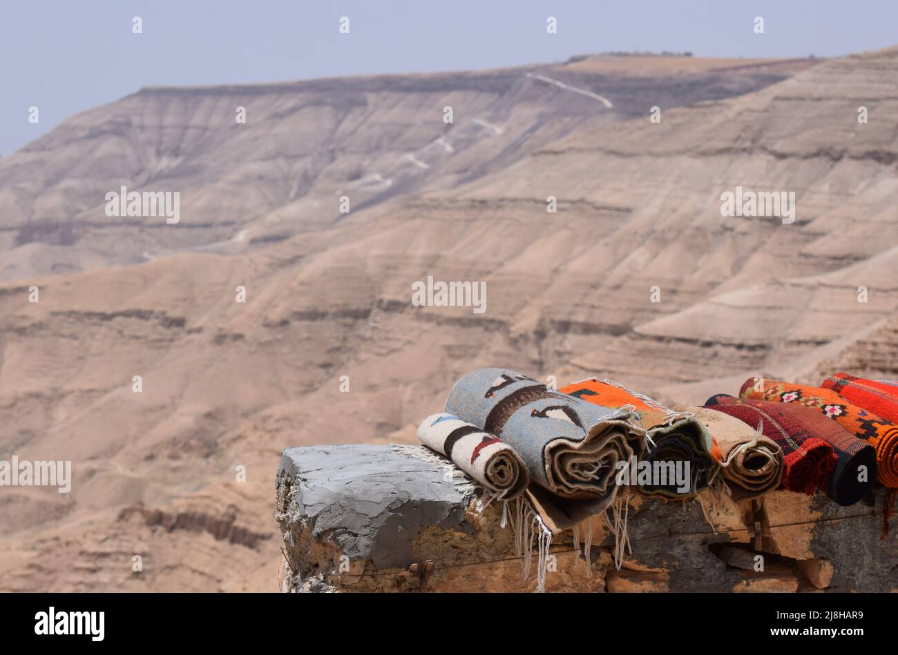 Tapis de Beduin roulés pour la vente empilés sur un mur dans une aire de repos sur le bord de la route Kings Highway en Jordanie Banque D'Images